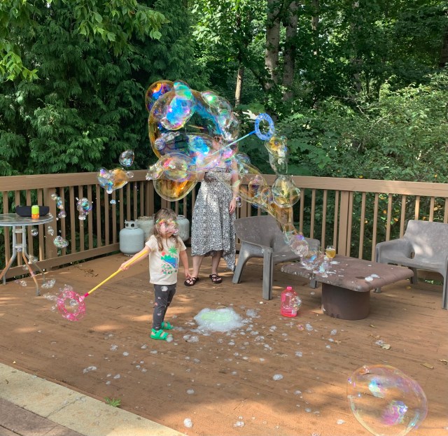 an adult and child play with bubbles
